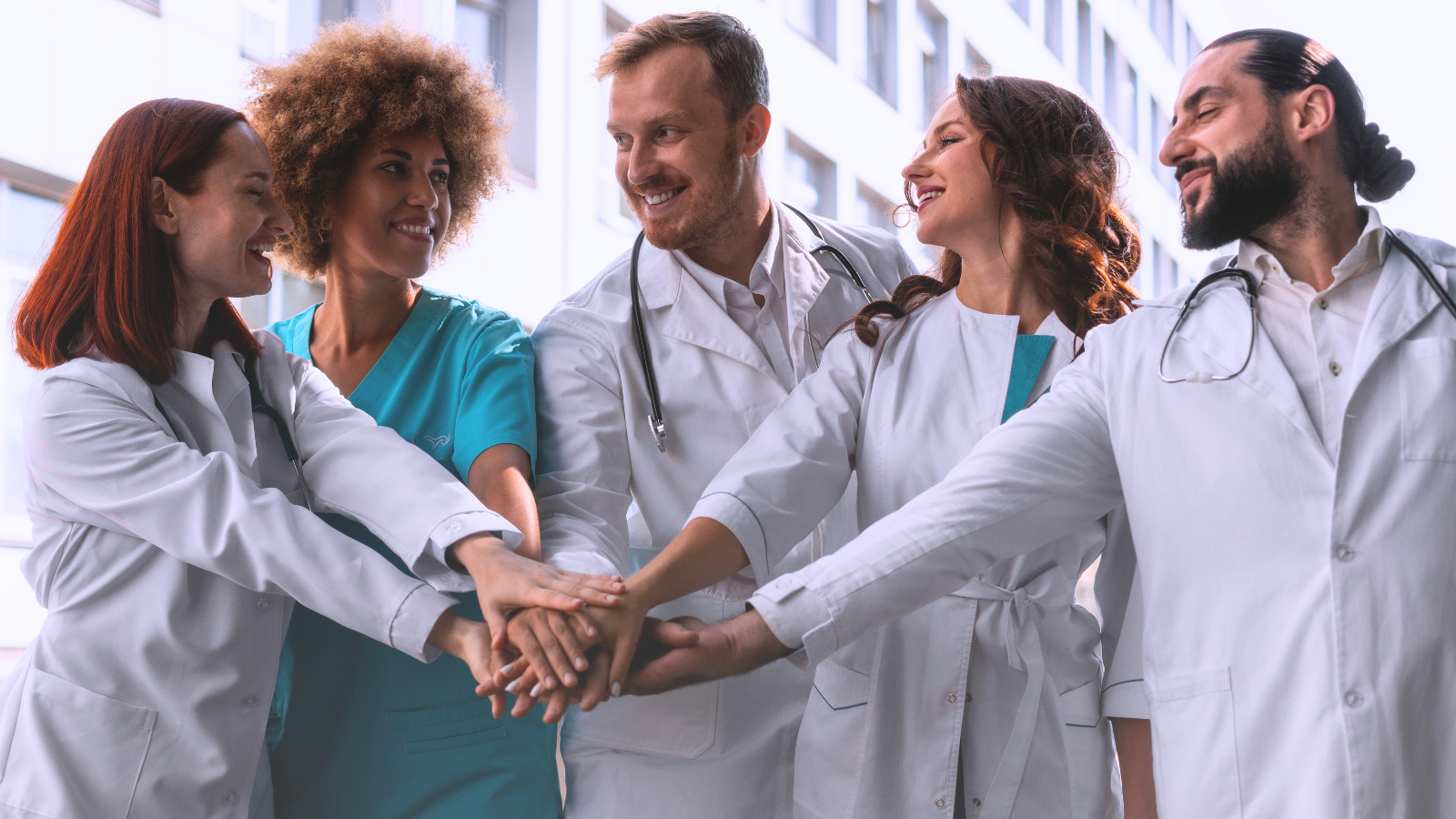 A group of doctors, representing the Healthcare Translations Team and united by their expertise, is holding hands in solidarity in front of a hospital building.