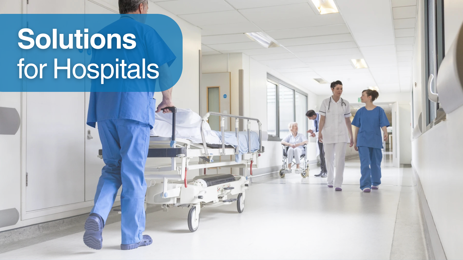 A nurse transporting a patient on a stretcher in a hospital corridor. Next to him, patients and nurses walk calmly. At the top left, a text reading Solutions for Hospitals.