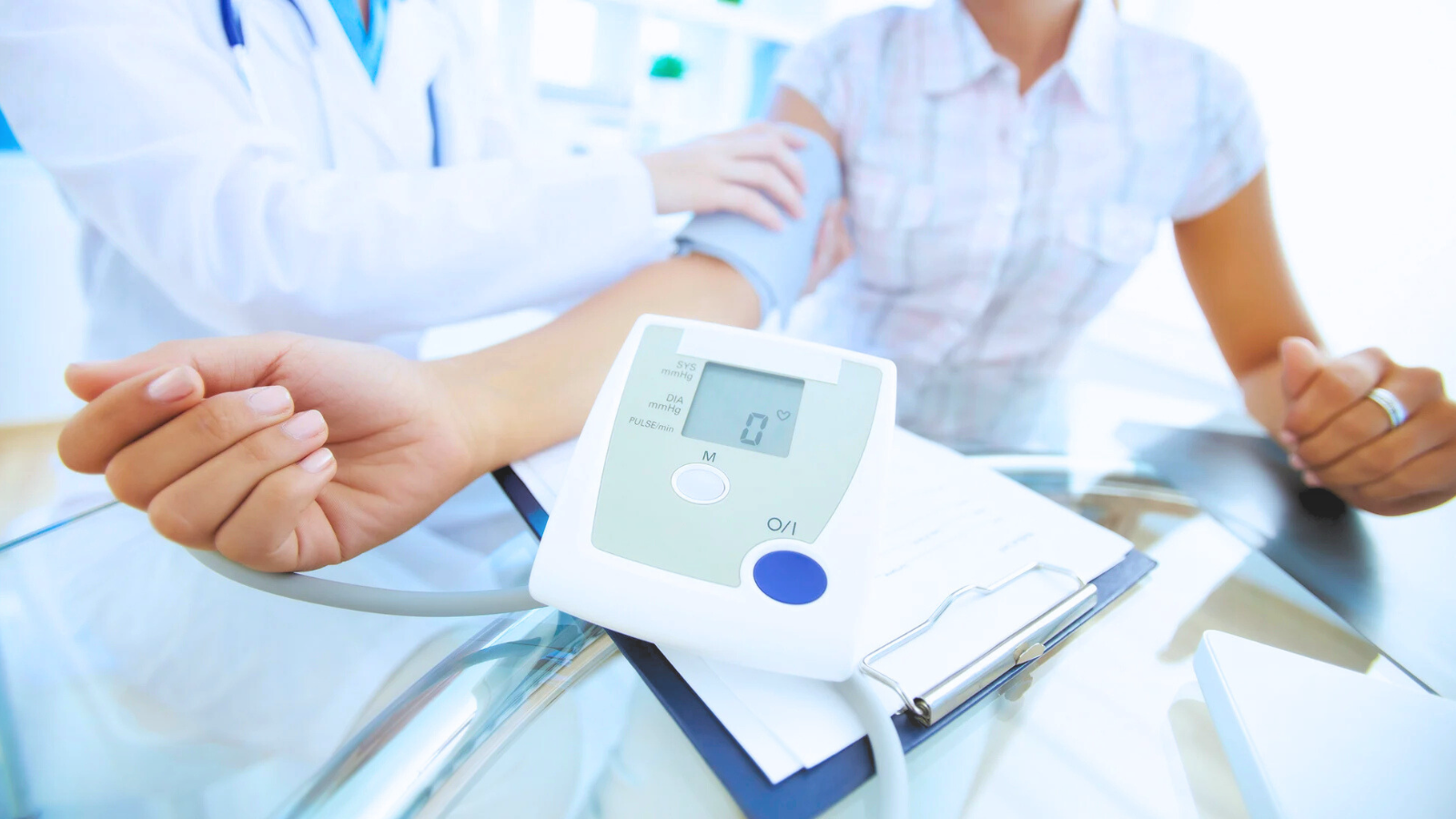 A doctor measures a patient's blood pressure using a sphygmomanometer in a clinical setting.